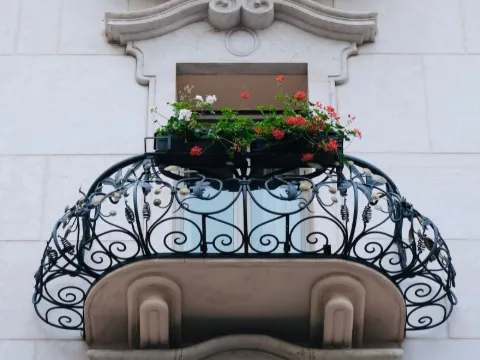 Deux balcons en corbeille à volutes de fer forgé sur une façade de pierre claire