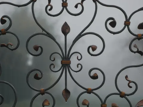 Détail de volutes en fer forgé noir à feuilles et bagues de cuivre, fond gris flou