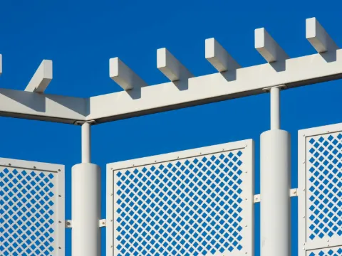 Panneaux de métal blanc à motif de losanges ajourés sous une pergola