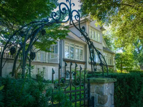 Portillon en fer forgé à arceau et volutes ouvrant sur le jardin d'une maison