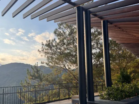 Poteaux d'acier sombre et lames de bois d'une pergola contemporaine au-dessus de marches, vue sur la montagne