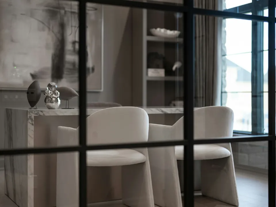 Verrière à carreaux d'acier noir au premier plan devant une salle à manger en marbre
